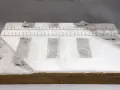 Miniatura terenu przy torze kolejowym z betonowymi płytami i kamieniami.