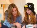Zaczarowana zagroda bohaterowie: mama czyta książkę dziecku w stroju pingwinka.