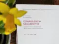 Żółty narcyz obok książki "Odwaga bycia nielubianym". Autorzy pokazują, jak odnaleźć wolność i odmienić życie.