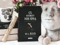 Książka "Ci, którzy nie śpią" M.L. Rio, obok kubka i ozdobnej głowy. Nawet jeśli jesteśmy złoczyńcami, warto po nią sięgnąć.