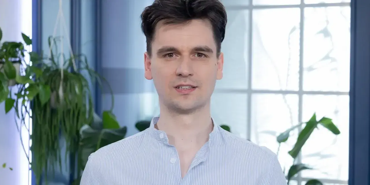 Piotr, w niebieskiej koszuli w paski, wygląda jakby właśnie skończył czytać książkę, a teraz opowiada o niej z pasją.