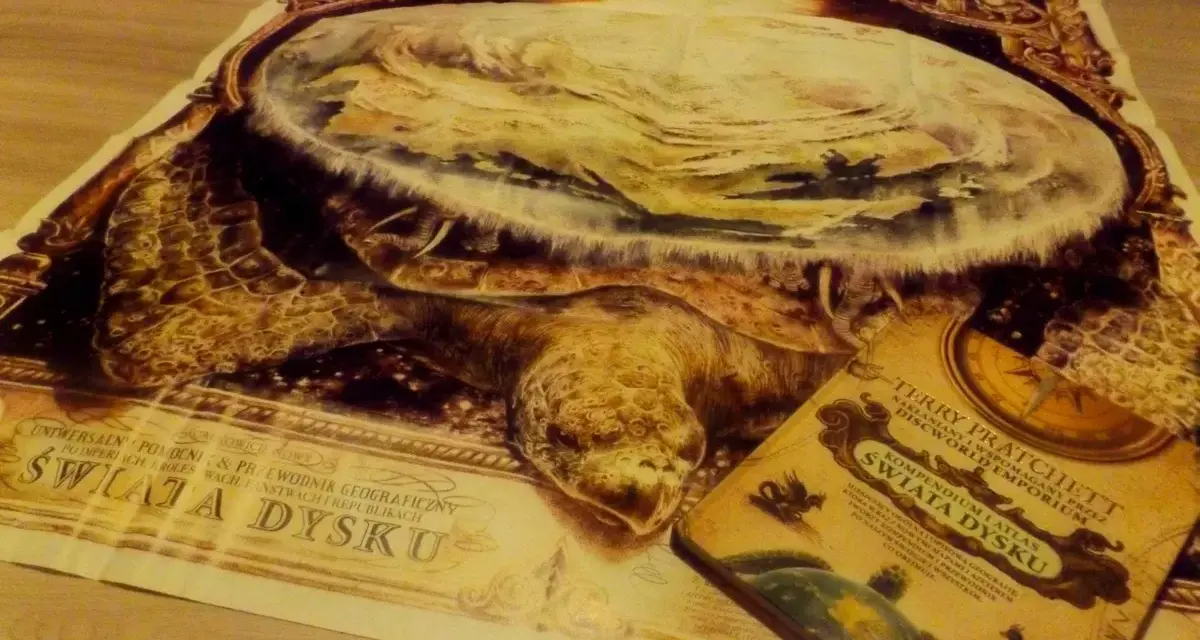 Mapa świata dysku z Wielkim A'Tuinem i książka Terry'ego Pratchetta "Świat Dysku".