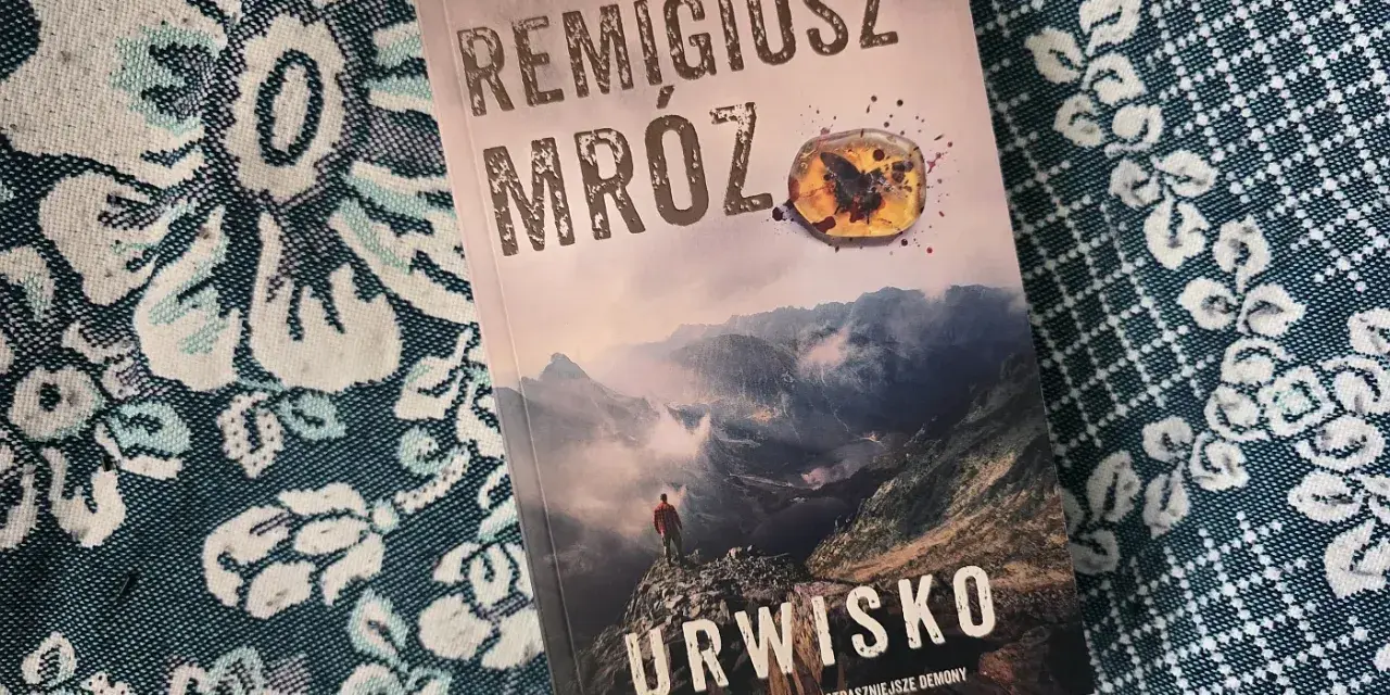 Okładka najnowszej książki Remigiusza Mroza "Urwisko". Góry, mgła i samotna postać na szczycie.