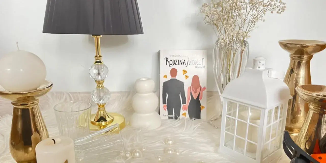 Książka "Rodzina Monet. Diament" wśród świec, złotych świeczników i ozdób.