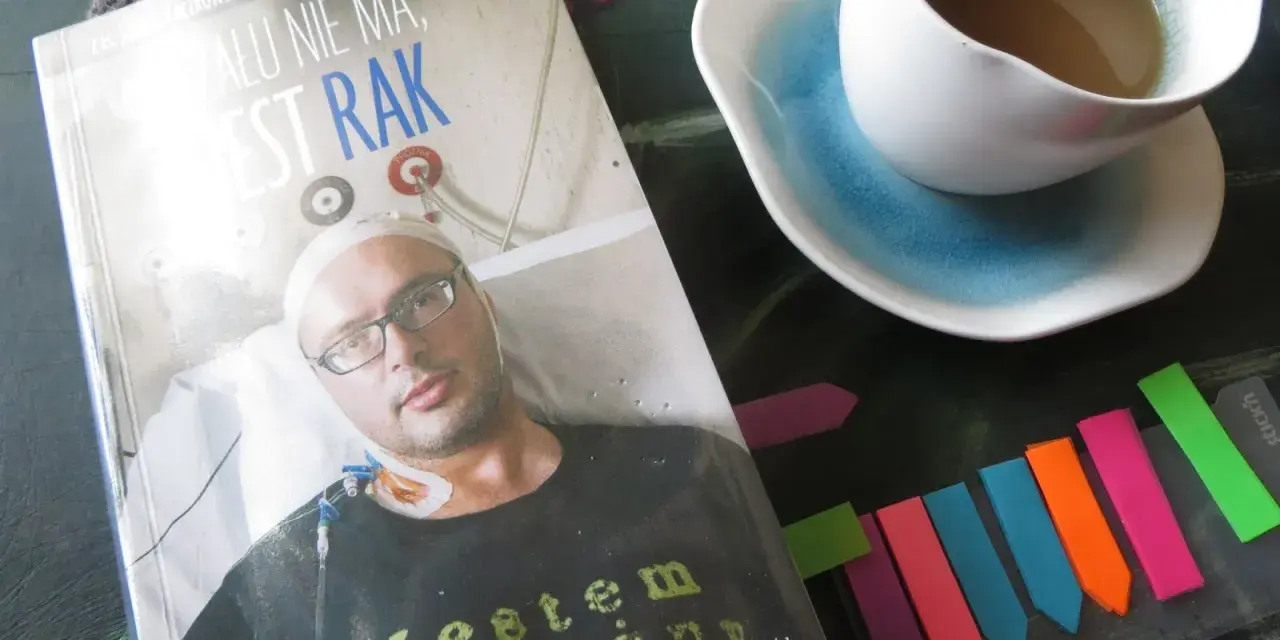 Książka "Żalu nie ma, jest rak" z wizerunkiem autora, obok filiżanka kawy i kolorowe zakładki.