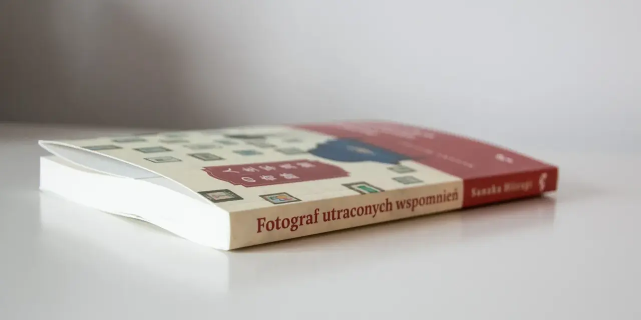 Książka "Fotograf utraconych wspomnień" z japońskimi znakami na okładce, leżąca na białym blacie.