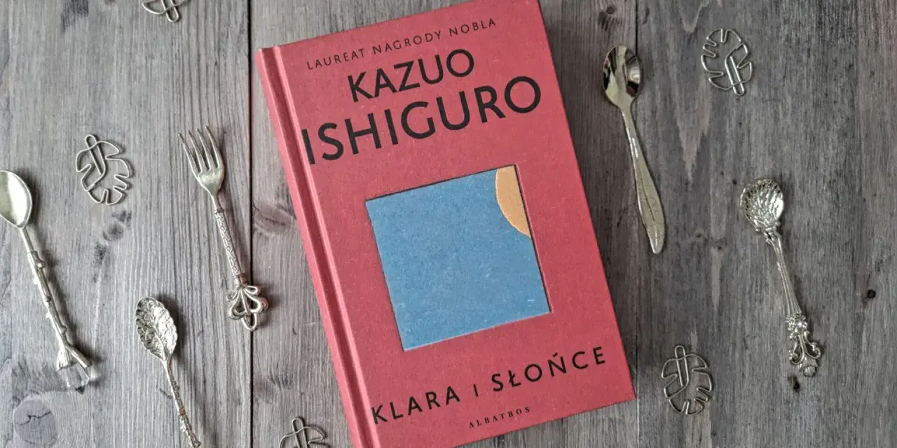 Książka "Klara i Słońce" Kazuo Ishiguro na drewnianym tle, otoczona ozdobnymi łyżeczkami i listkami.