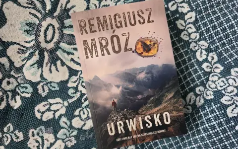 Okładka najnowszej książki Remigiusza Mroza "Urwisko". Góry, mgła i samotna postać na szczycie.