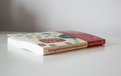 Książka "Fotograf utraconych wspomnień" z japońskimi znakami na okładce, leżąca na białym blacie.