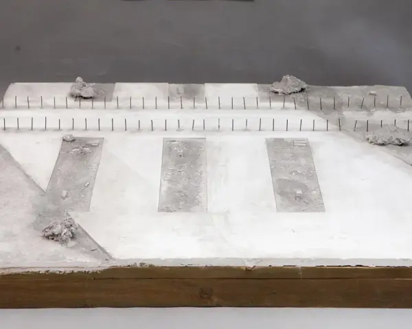Miniatura terenu przy torze kolejowym z betonowymi płytami i kamieniami.