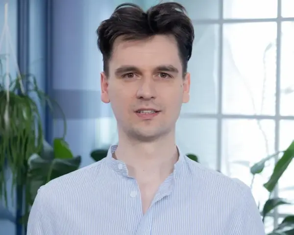 Piotr, w niebieskiej koszuli w paski, wygląda jakby właśnie skończył czytać książkę, a teraz opowiada o niej z pasją.