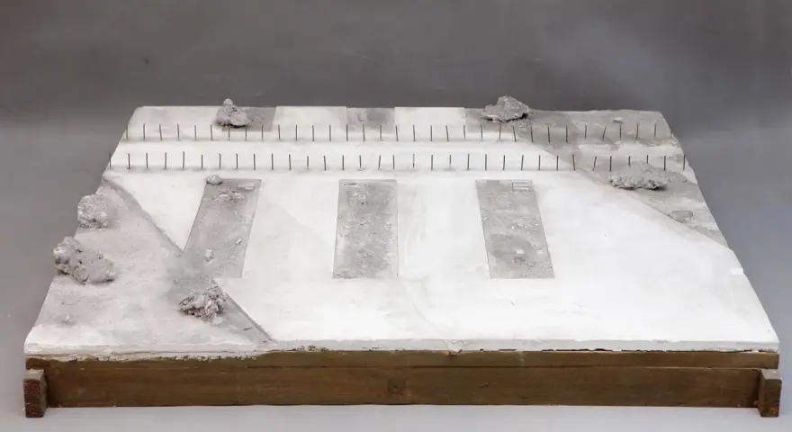 Miniatura terenu przy torze kolejowym z betonowymi płytami i kamieniami.