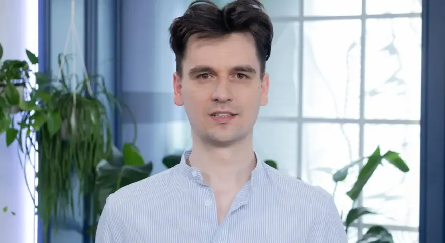 Piotr, w niebieskiej koszuli w paski, wygląda jakby właśnie skończył czytać książkę, a teraz opowiada o niej z pasją.