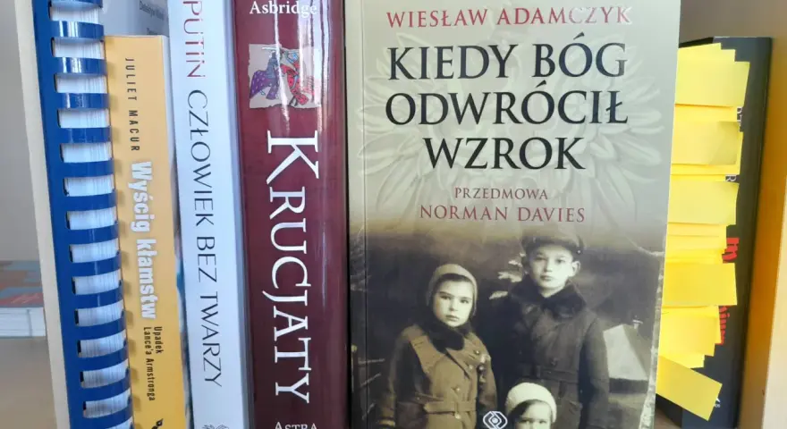 Okładka książki "Kiedy Bóg odwrócił wzrok" z portretem dzieci. Obok inne książki, w tym "Putin człowiek bez twarzy".