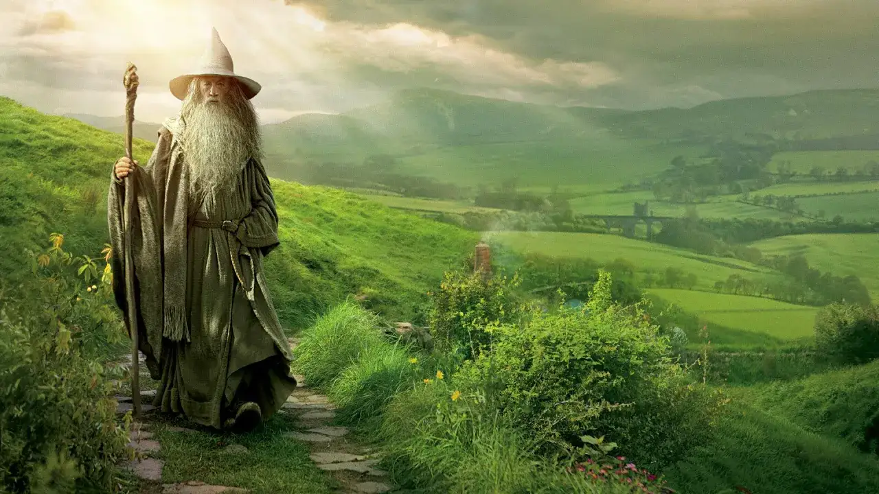 Gandalf, autor Władcy Pierścieni, stoi na ścieżce wśród zielonych wzgórz.