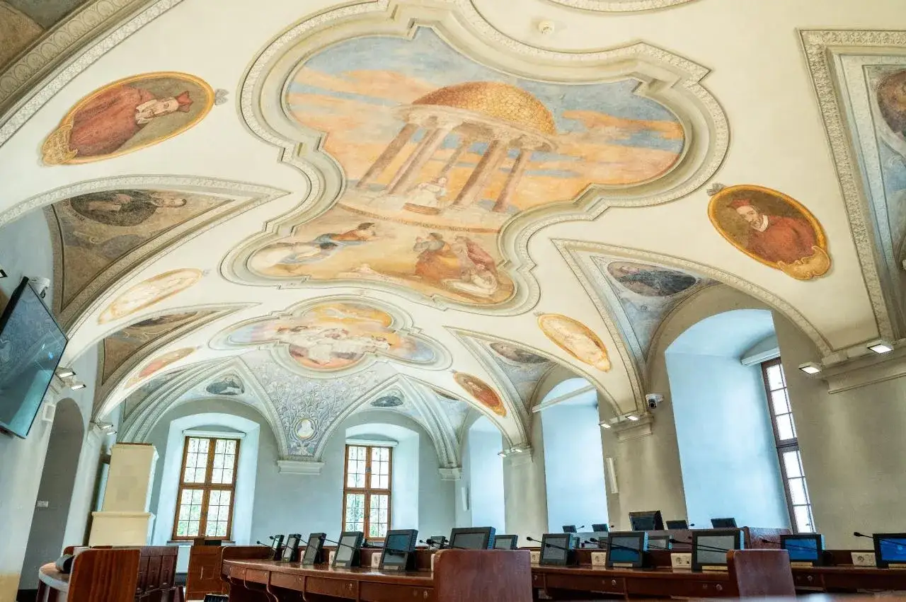Bogate malowidła na sklepieniu sali, ukazujące sceny i portrety, odzwierciedlają barok charakterystykę epoki.
