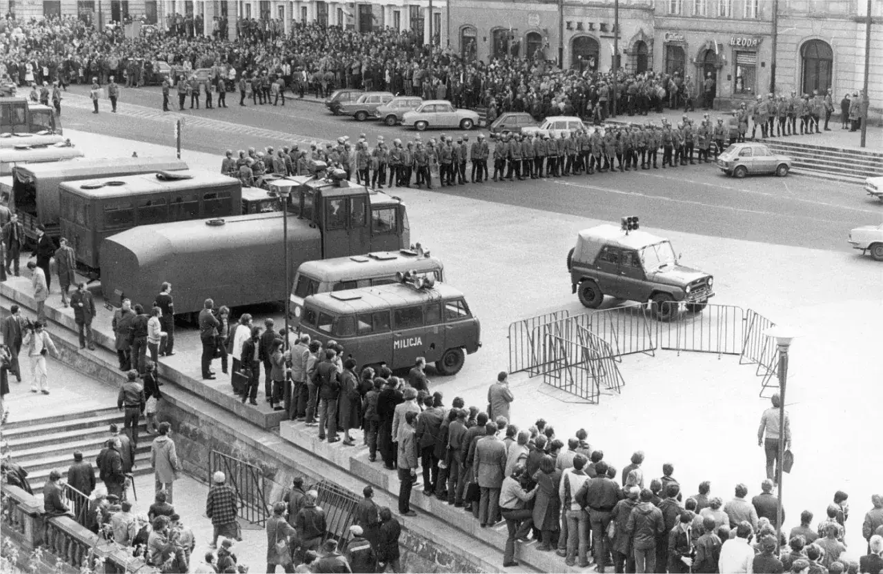 Tłum ludzi w Warszawie, milicja i wojsko pilnują porządku. Profesor Andrews mógł być świadkiem tych wydarzeń.