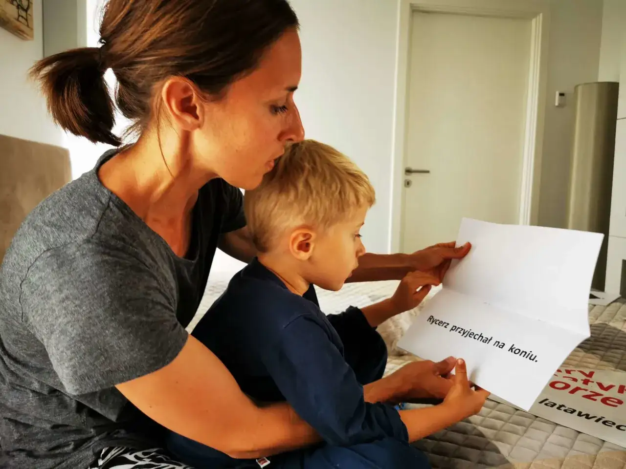 Mama z synem czytają lektury klasa 1. Na kartce widnieje napis 